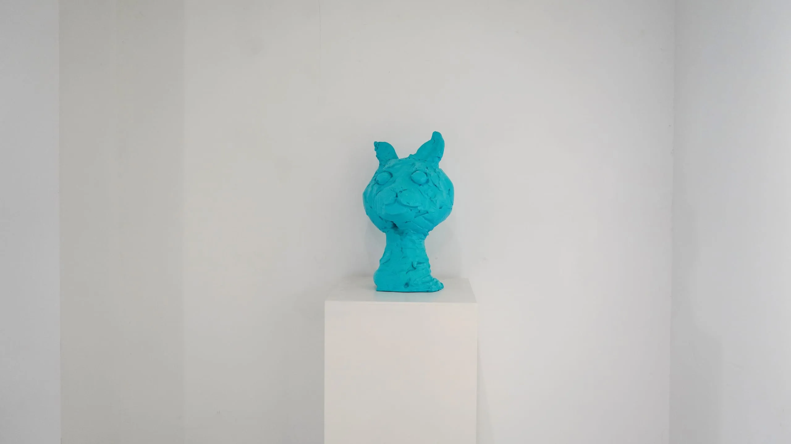 Animals — A turquoise cat bust on a white plinth, its surface left rough and hand-worked.